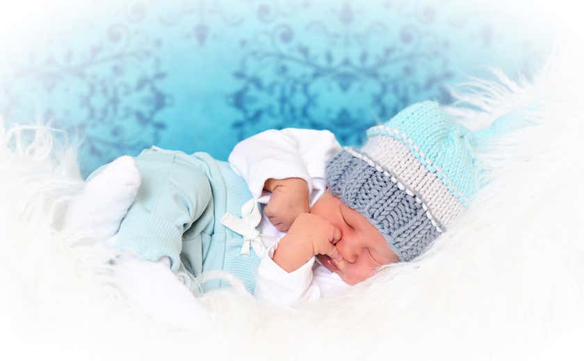 Baby schläft auf weißem Fell mit blauer Mütze Fotograf PB Studios aus Achim
